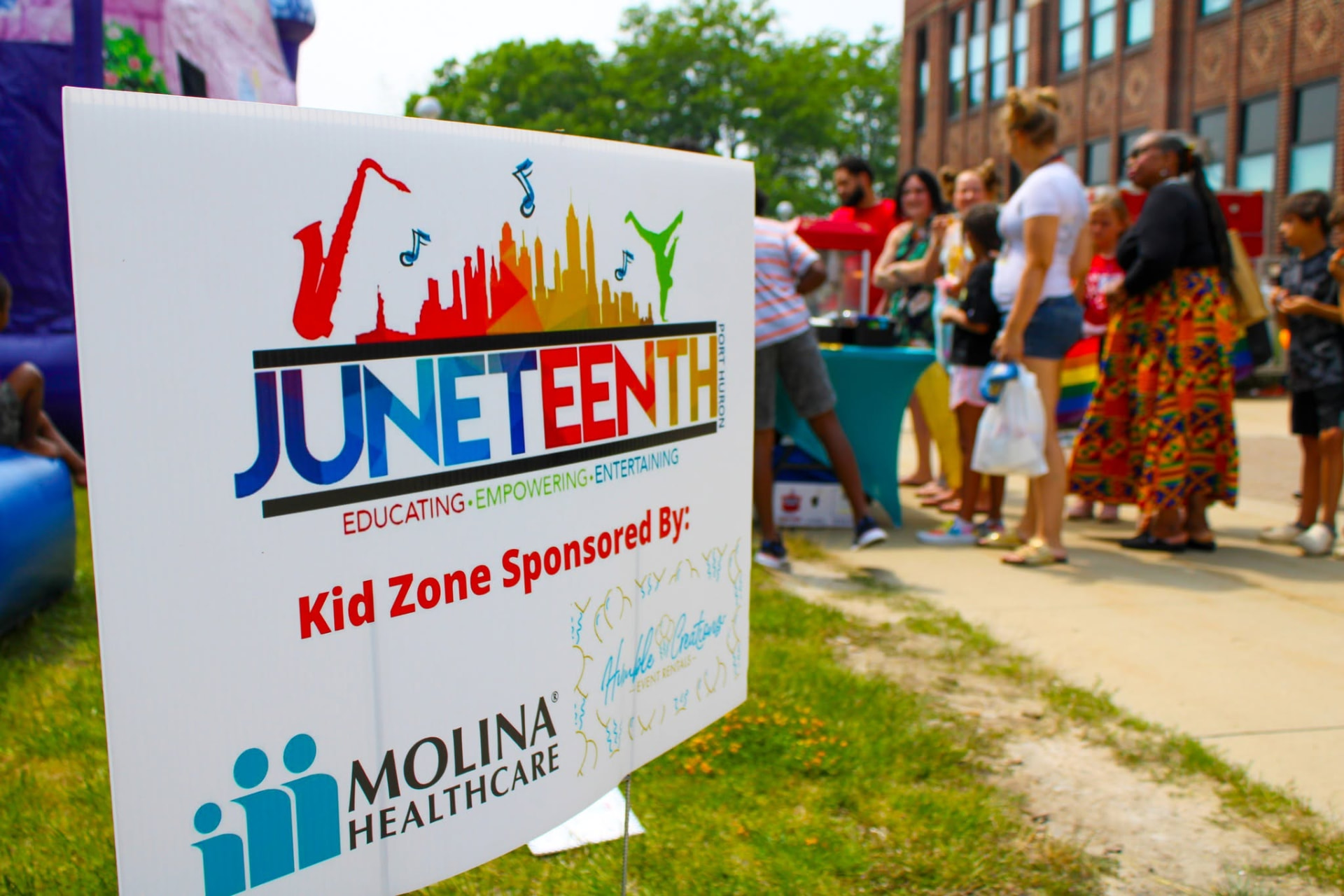 A Juneteenth festival sign with families gathered behind it